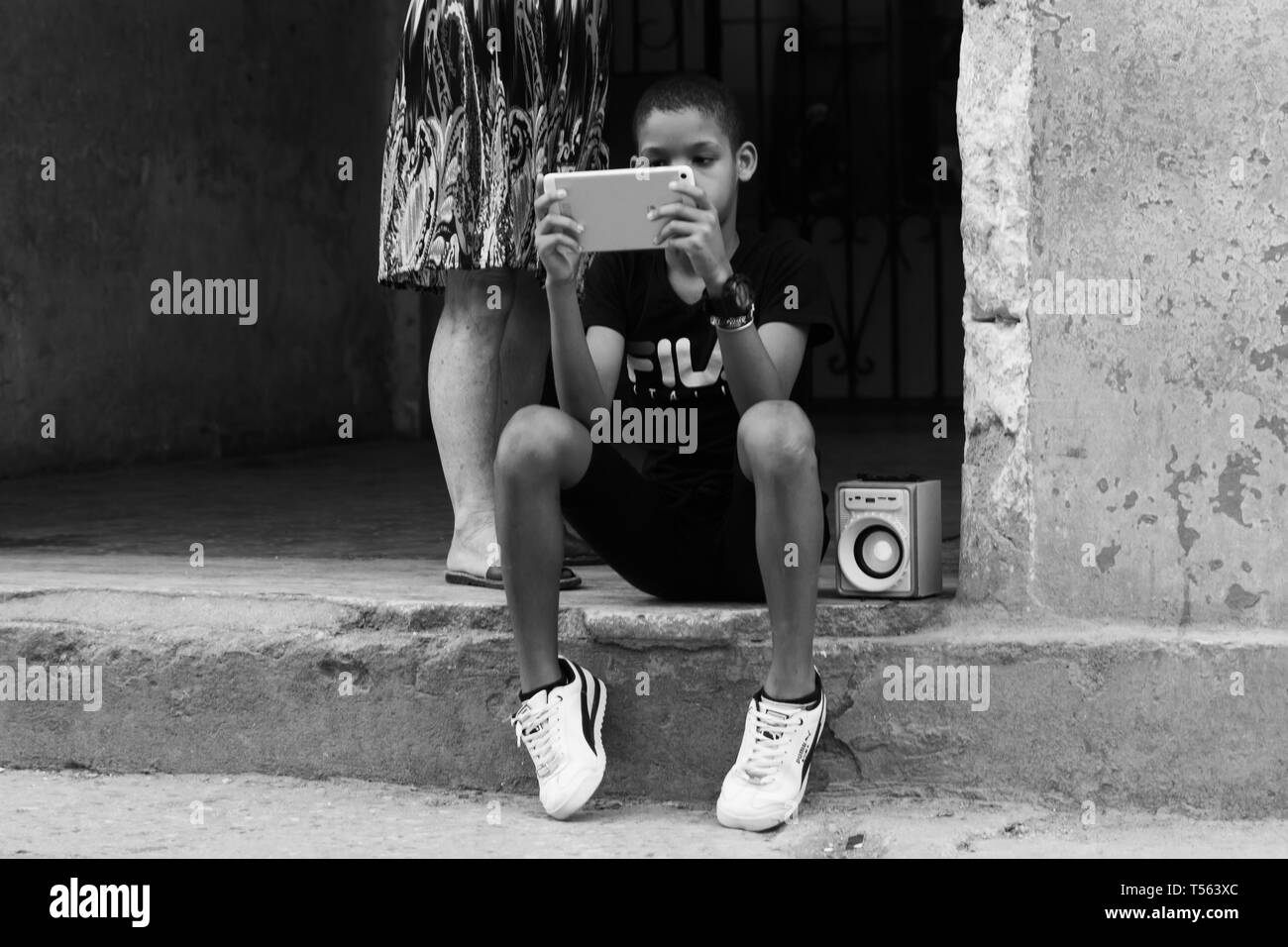 L'Avana, Cuba - Febbraio 2019: Ignota figli giocare gioco elettronico e ascoltare musica su un altoparlante per le strade di La Habana, Cuba nel febbraio 2019 Foto Stock