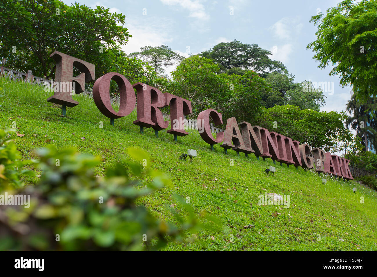 Un basso e laterale ad angolo immagine del grande segnaletica che indica il nome di Fort Canning Park su un pendio ripido, Singapore. Foto Stock