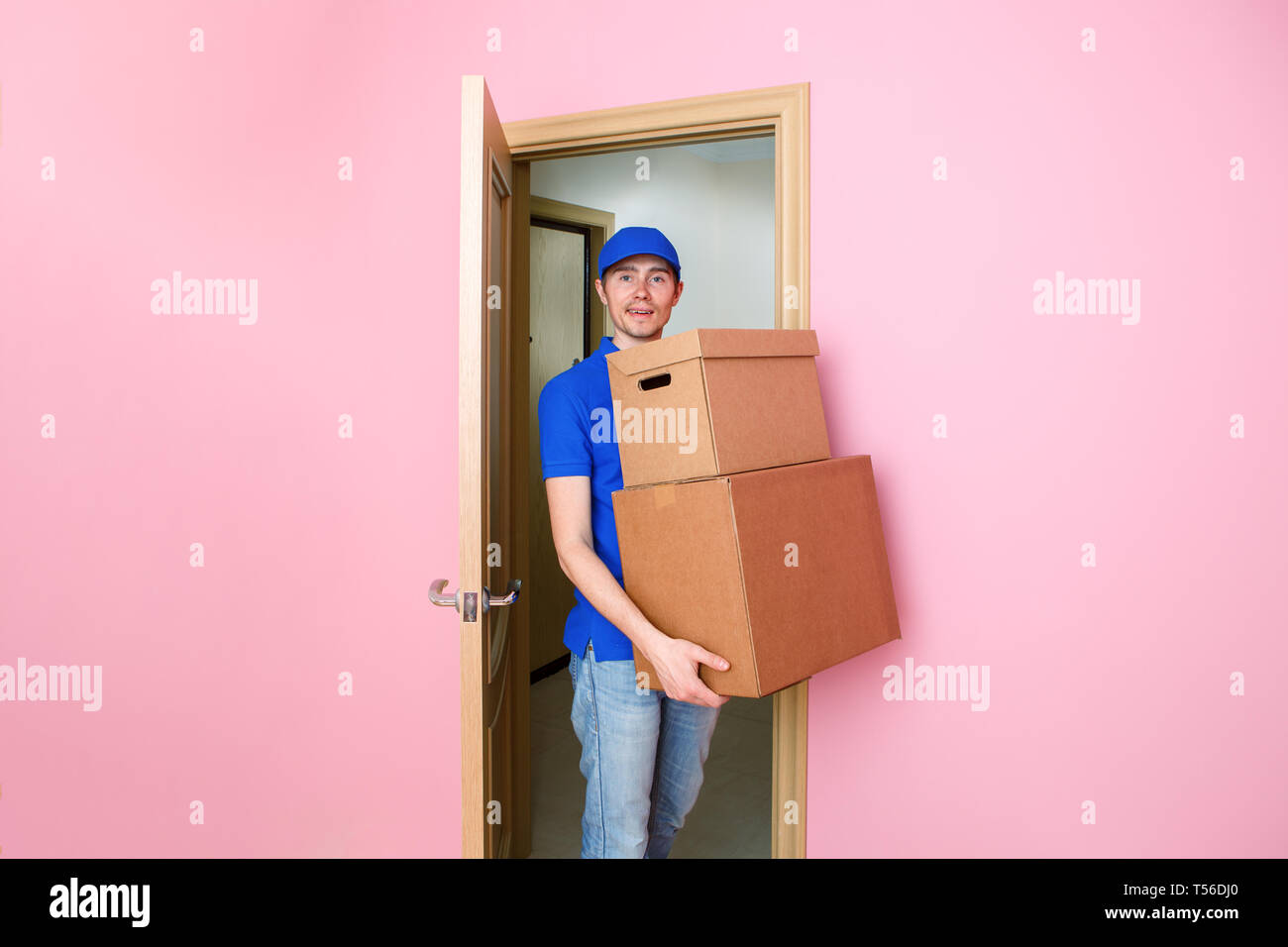 Foto di courier uomo in blu berretto da baseball con scatole di cartone in mani. Foto Stock