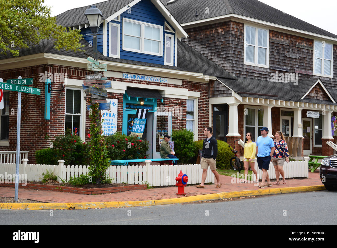 I turisti a piedi passato la rustica negozi del centro di Manteo sull'esterno della Banca Isola Roanoke, North Carolina. Foto Stock