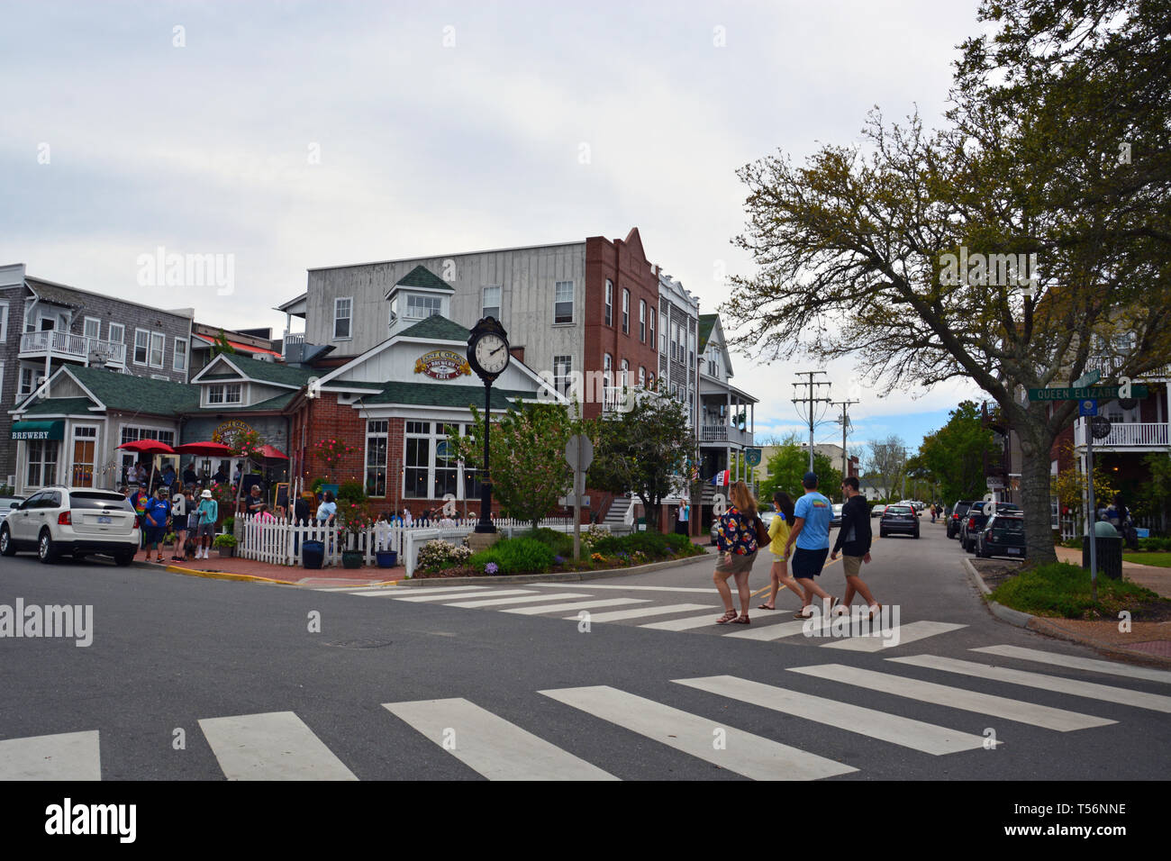 I turisti a piedi passato la rustica negozi del centro di Manteo sull'esterno della Banca Isola Roanoke, North Carolina. Foto Stock