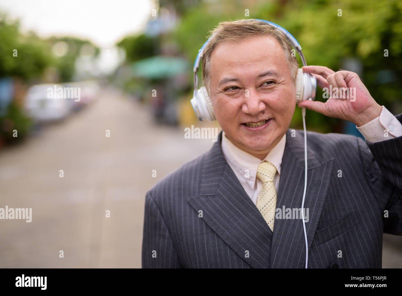 Maturo imprenditore asiatico l'ascolto di musica per le strade superarvi Foto Stock