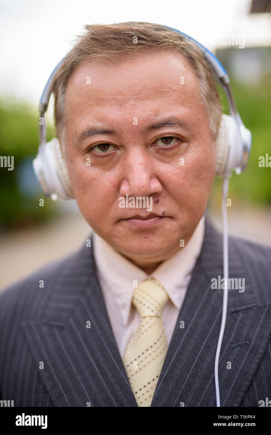 Maturo imprenditore asiatico l'ascolto di musica per le strade superarvi Foto Stock