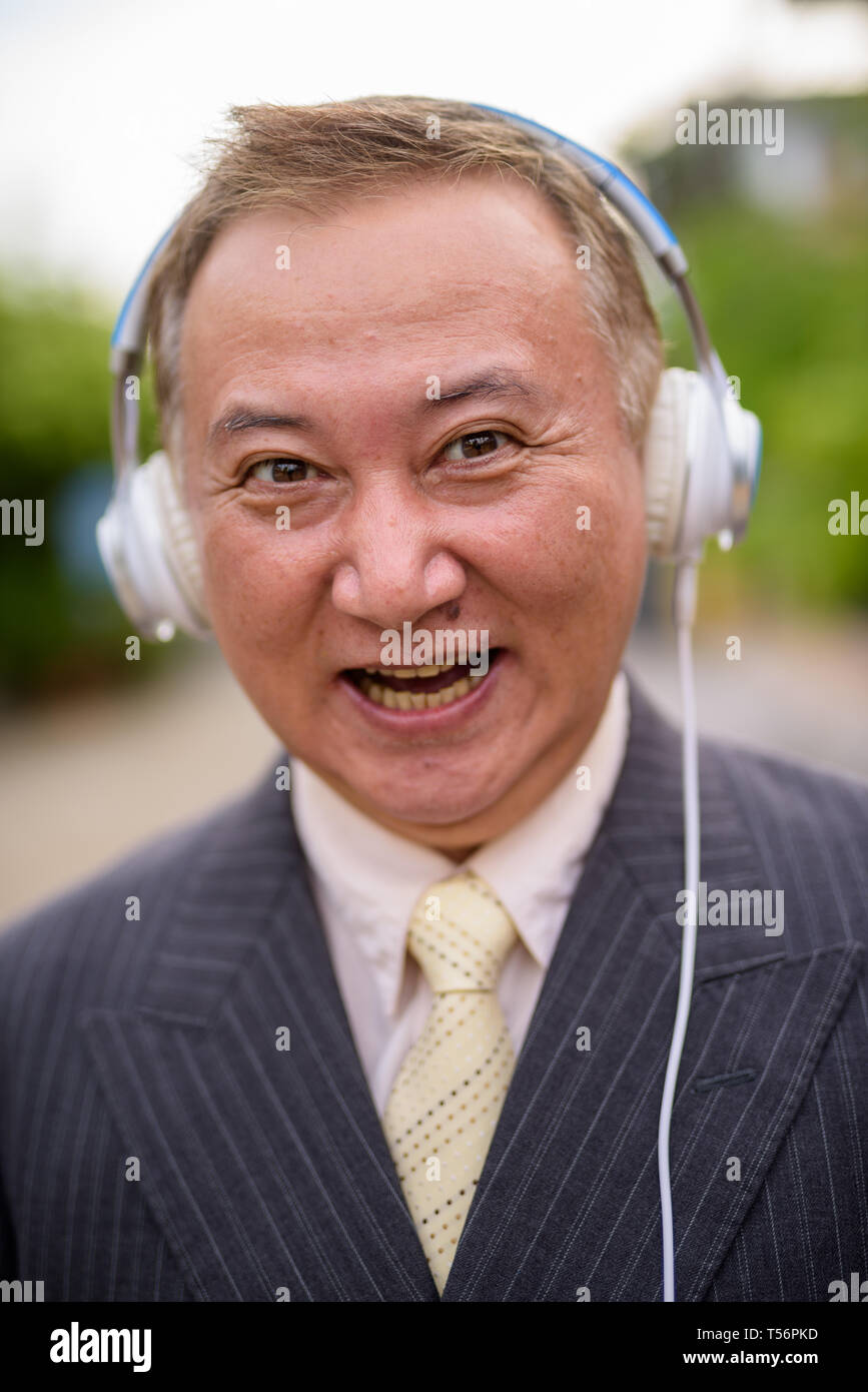 Maturo imprenditore asiatico l'ascolto di musica per le strade superarvi Foto Stock
