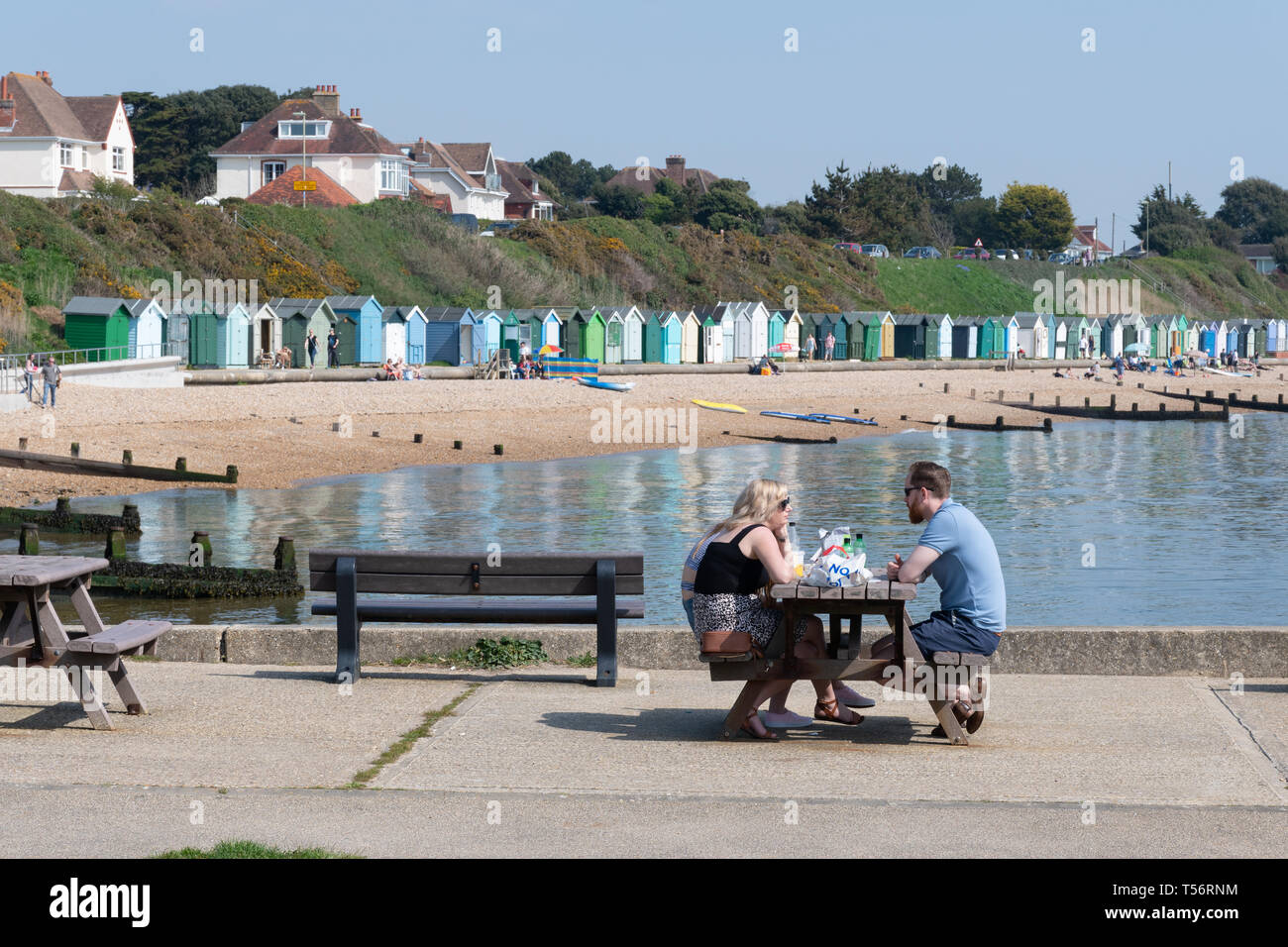 Coppia giovane avente un picnic e godendo di una soleggiata giornata di primavera sulla spiaggia a testa di collina in Hampshire, Regno Unito Foto Stock