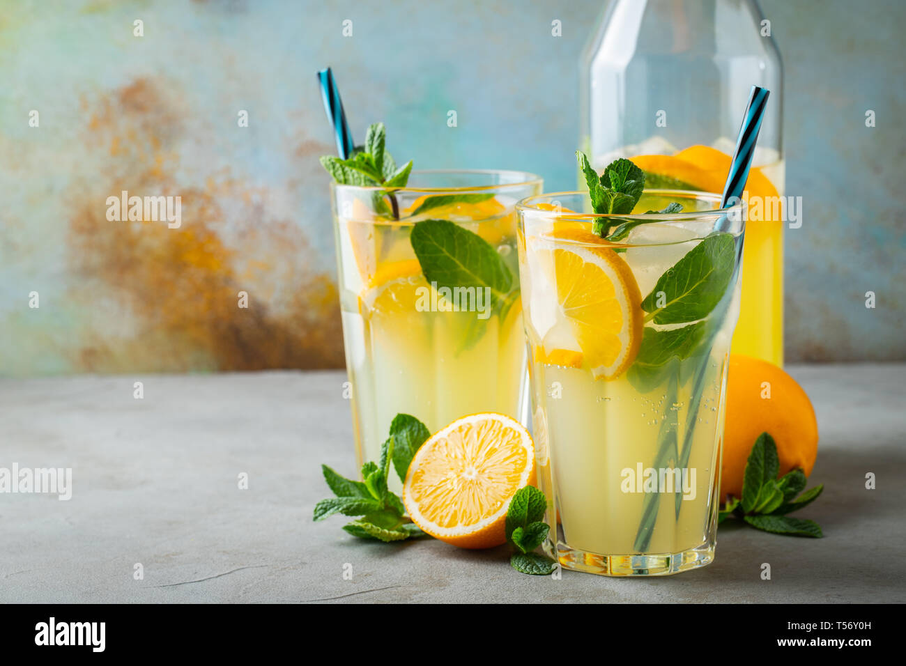 Due di vetro con una limonata o cocktail mojito con limone e menta, freddo bevanda rinfrescante o una bevanda con ghiaccio sul rustico sfondo blu. Copia dello spazio. Foto Stock