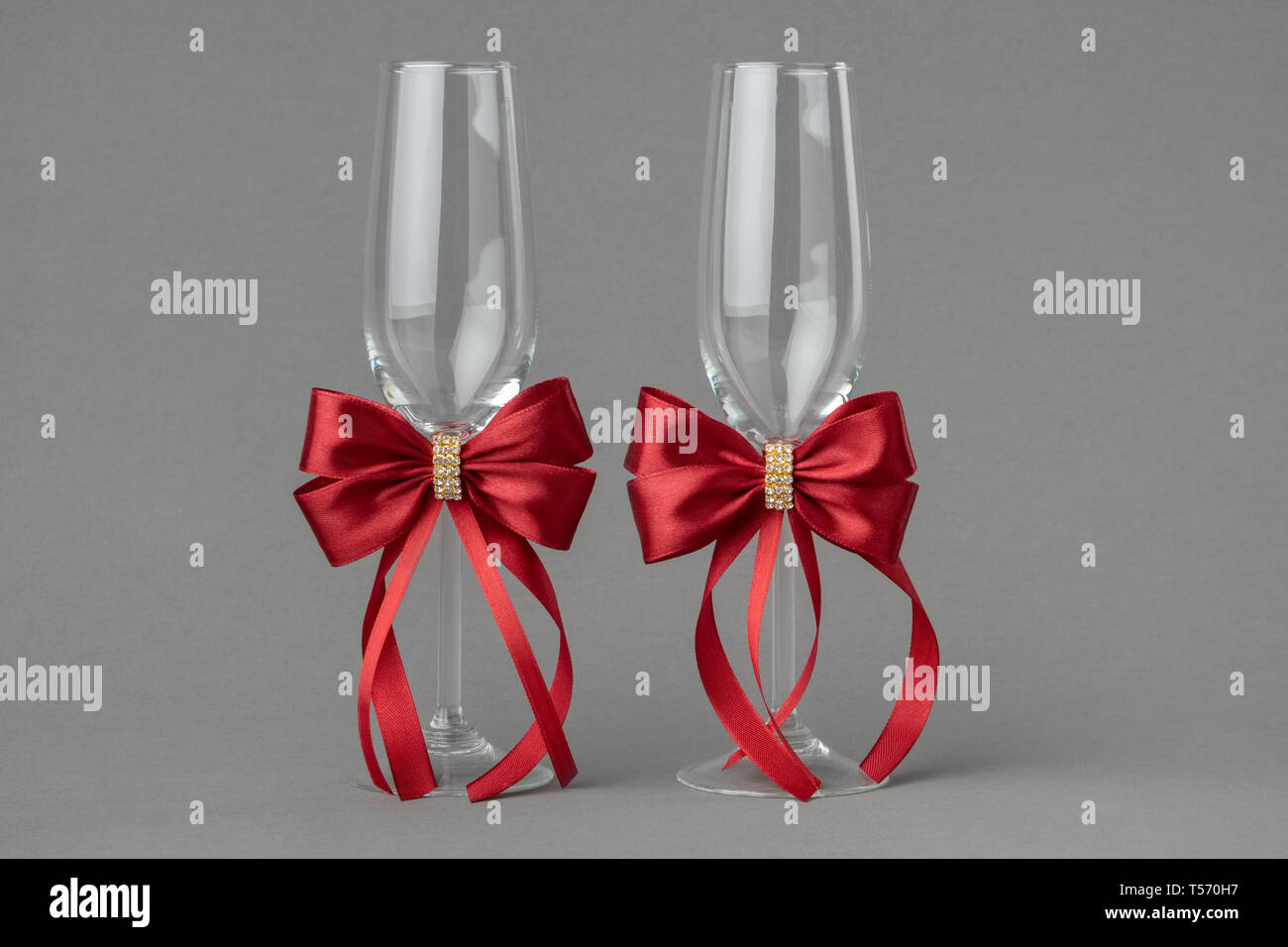 Matrimonio di due bicchieri di vino decora con seta rossa archi. Foto Stock