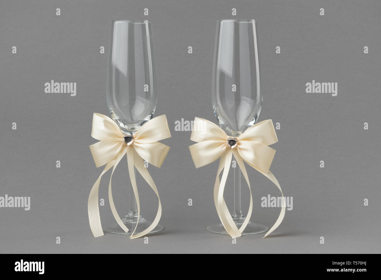Matrimonio di due bicchieri di vino decorate con nastri di color crema. Foto Stock