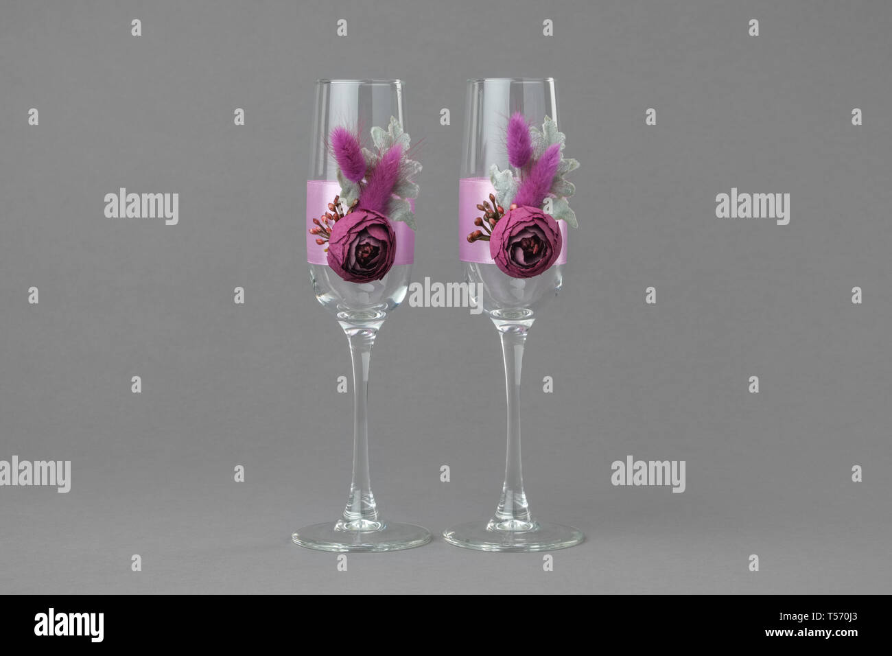 Due decorate wedding bicchieri di vino su sfondo grigio. Foto Stock