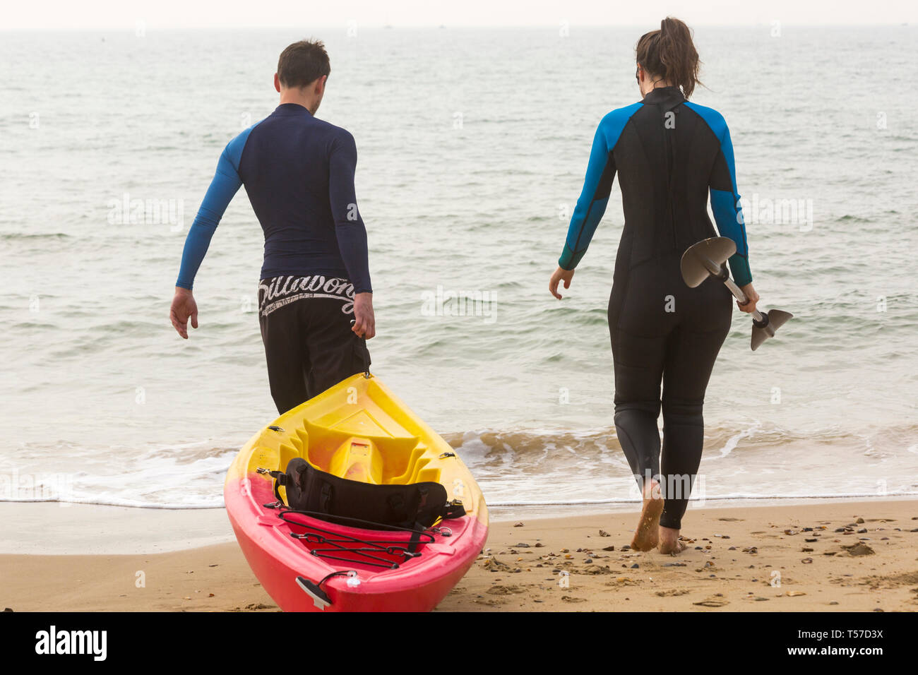 Bournemouth Dorset, Regno Unito. 22 apr, 2019. Regno Unito meteo: dopo un inizio nebuloso il glorioso meteo continua con caldo e soleggiato, come testa beachgoers al mare per godere del calore e del sole a Bournemouth spiagge del Lunedì di Pasqua prima che i cambiamenti climatici e il ritorno al lavoro. Paio di andare in kayak - giovane a piedi in mare con il kayak. Credito: Carolyn Jenkins/Alamy Live News Foto Stock