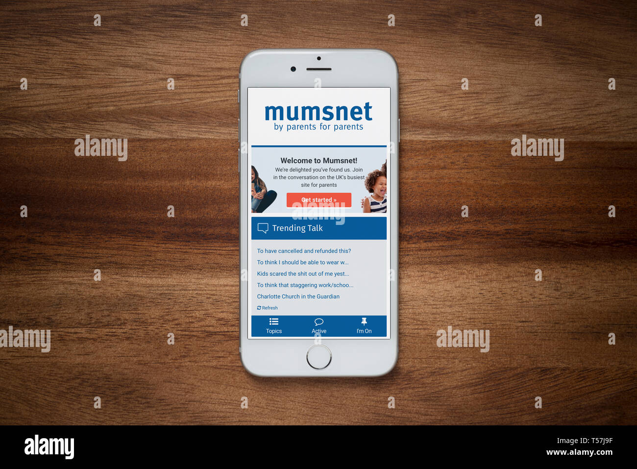 Un iPhone che mostra il sito web di Mumsnet poggia su una semplice tavola di legno (solo uso editoriale). Foto Stock