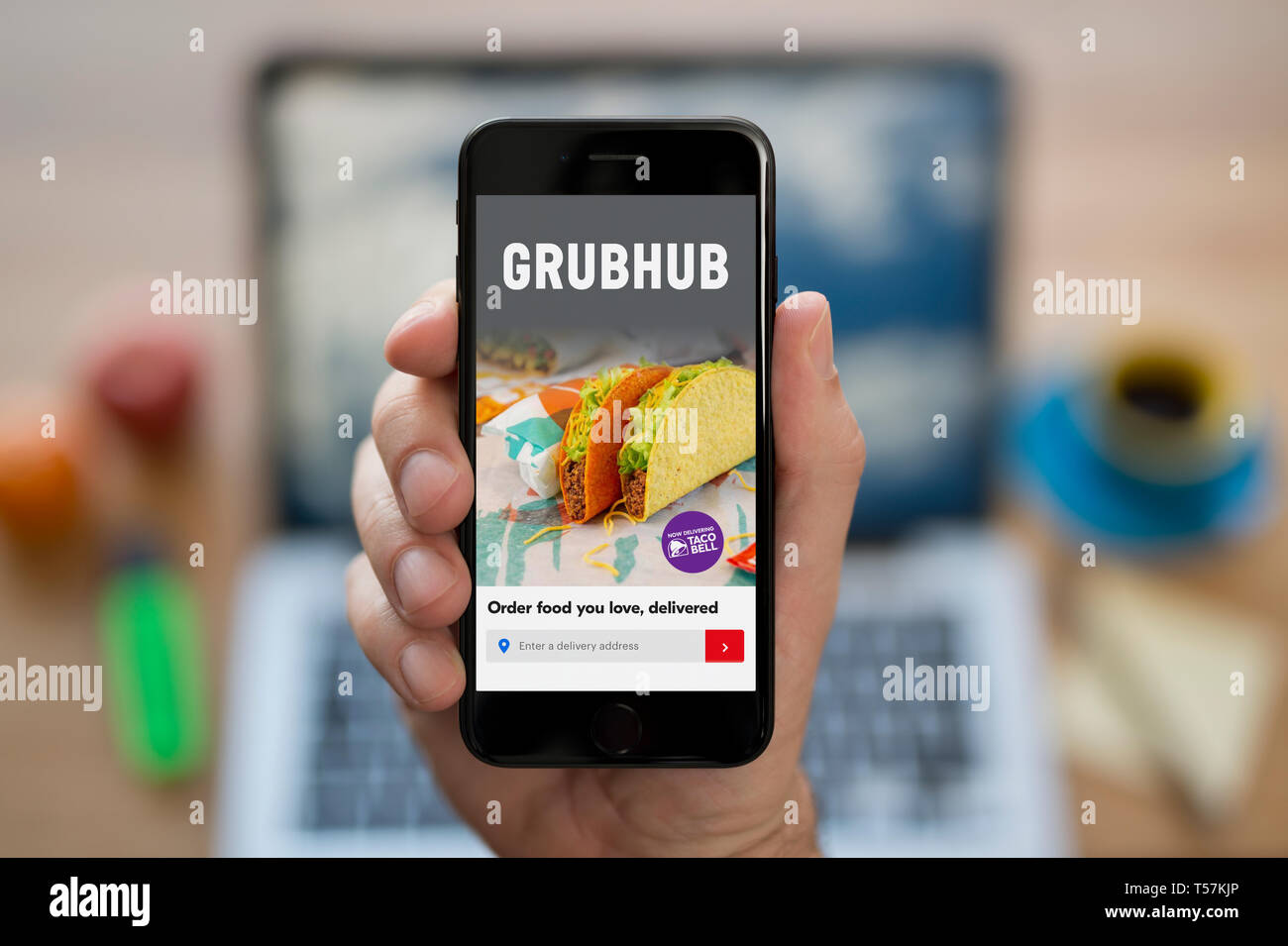 Un uomo guarda al suo iPhone che visualizza il logo Grubhub (solo uso editoriale). Foto Stock