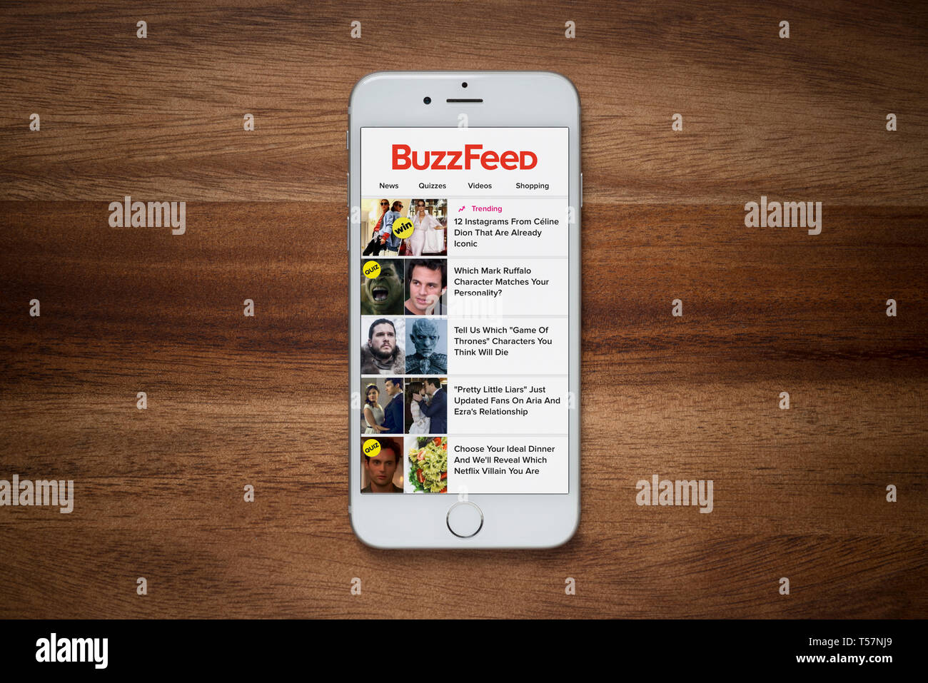 Un iPhone che mostra il sito Buzzfeed poggia su una semplice tavola di legno (solo uso editoriale). Foto Stock