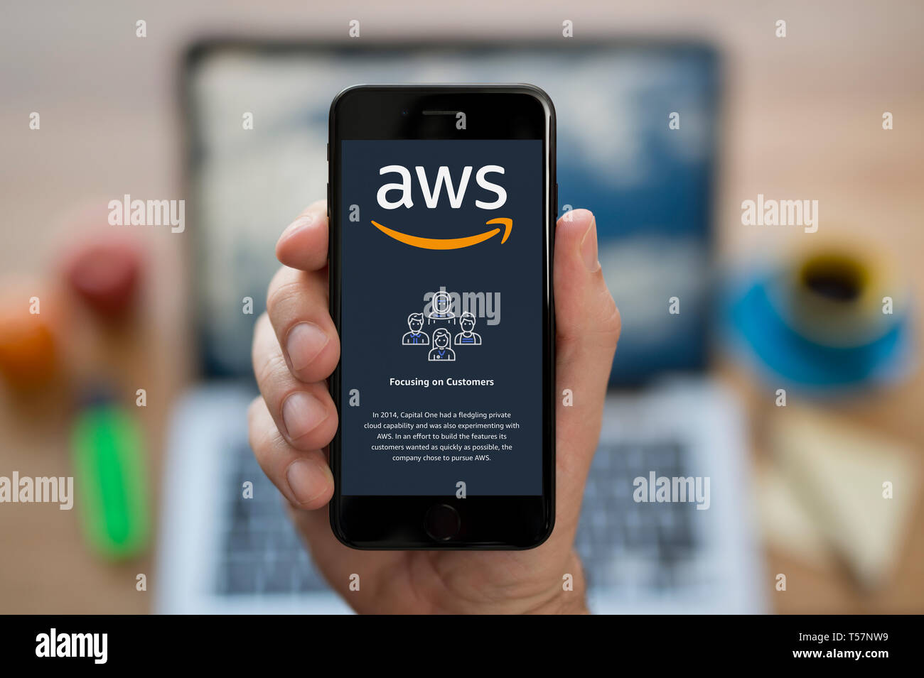 Un uomo guarda al suo iPhone che visualizza il Amazon Web Services (AWS) il logo (solo uso editoriale). Foto Stock