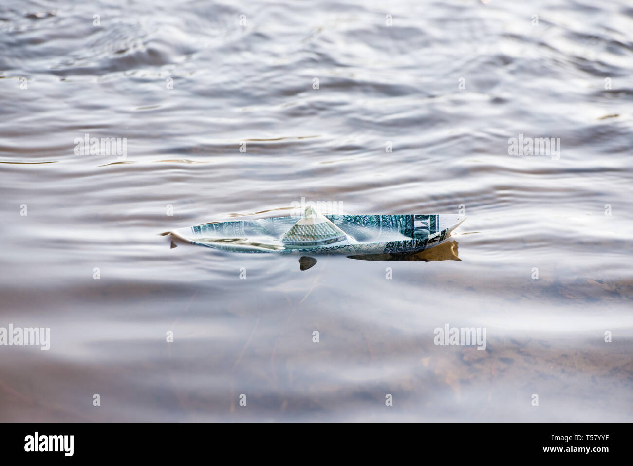 Una barca di carta da un dollaro è in pericolo. Il dollaro è che affonda nell'acqua. Immagine simbolica. Foto Stock