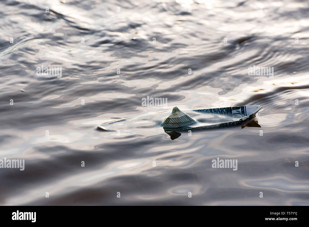 Una barca di carta da un dollaro è in pericolo. Il dollaro è che affonda nell'acqua. Immagine simbolica. Foto Stock