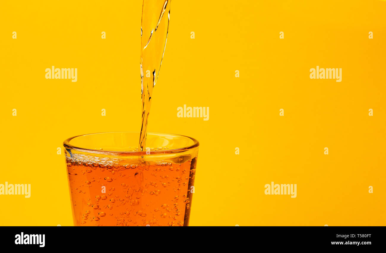 Il succo di mela versando in vetro, isolato su sfondo giallo Foto Stock