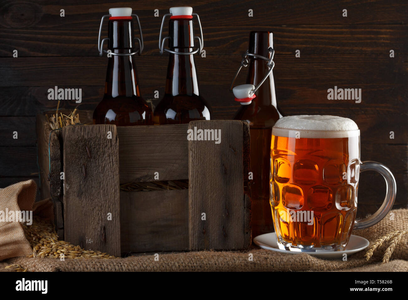 Bicchiere da birra con bottiglie di birra in casse di legno su tela stoffa Foto Stock