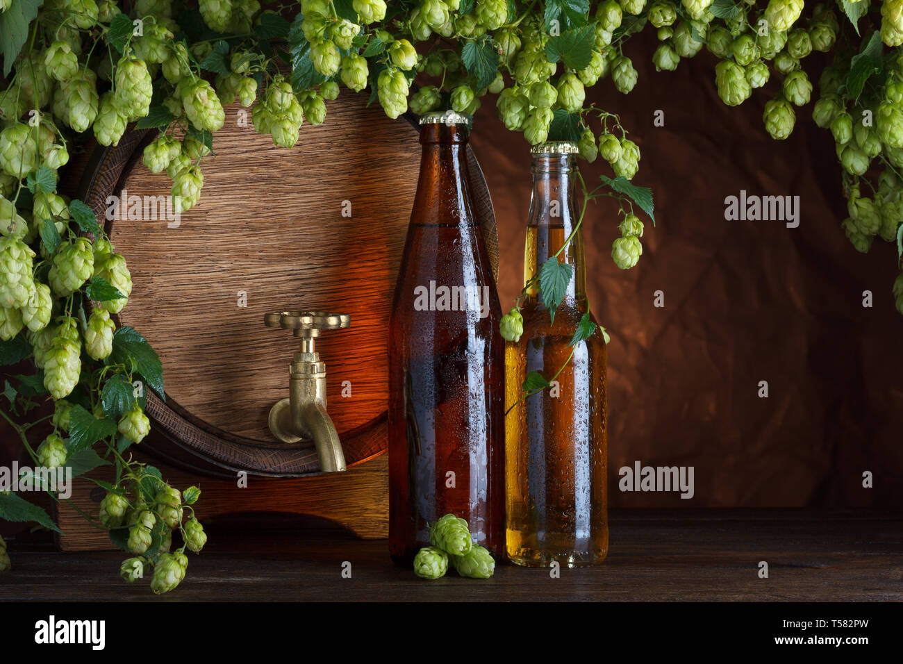 Le bottiglie di birra con il barile di birra e luppolo fresco cornice still-life Foto Stock