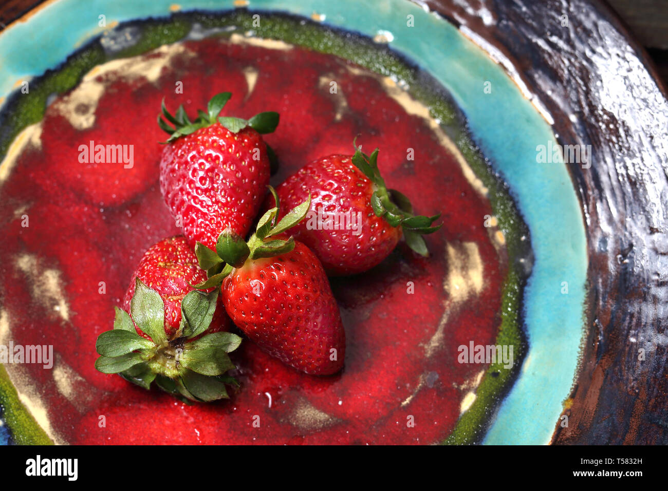 Una composizione di succosa, rosso Fragole su una rossa piastra ceramica. Composizione orizzontale, vista dall'alto Foto Stock