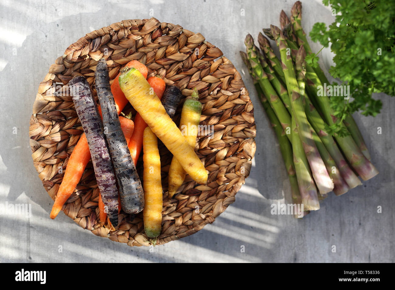 Colorate le carote e gli asparagi verdi. Il cestello con le verdure su un banco di cucina Foto Stock