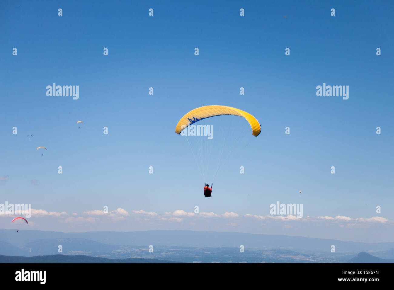 Gli uomini in volo in parapendio nel cielo blu in una giornata di sole Foto Stock