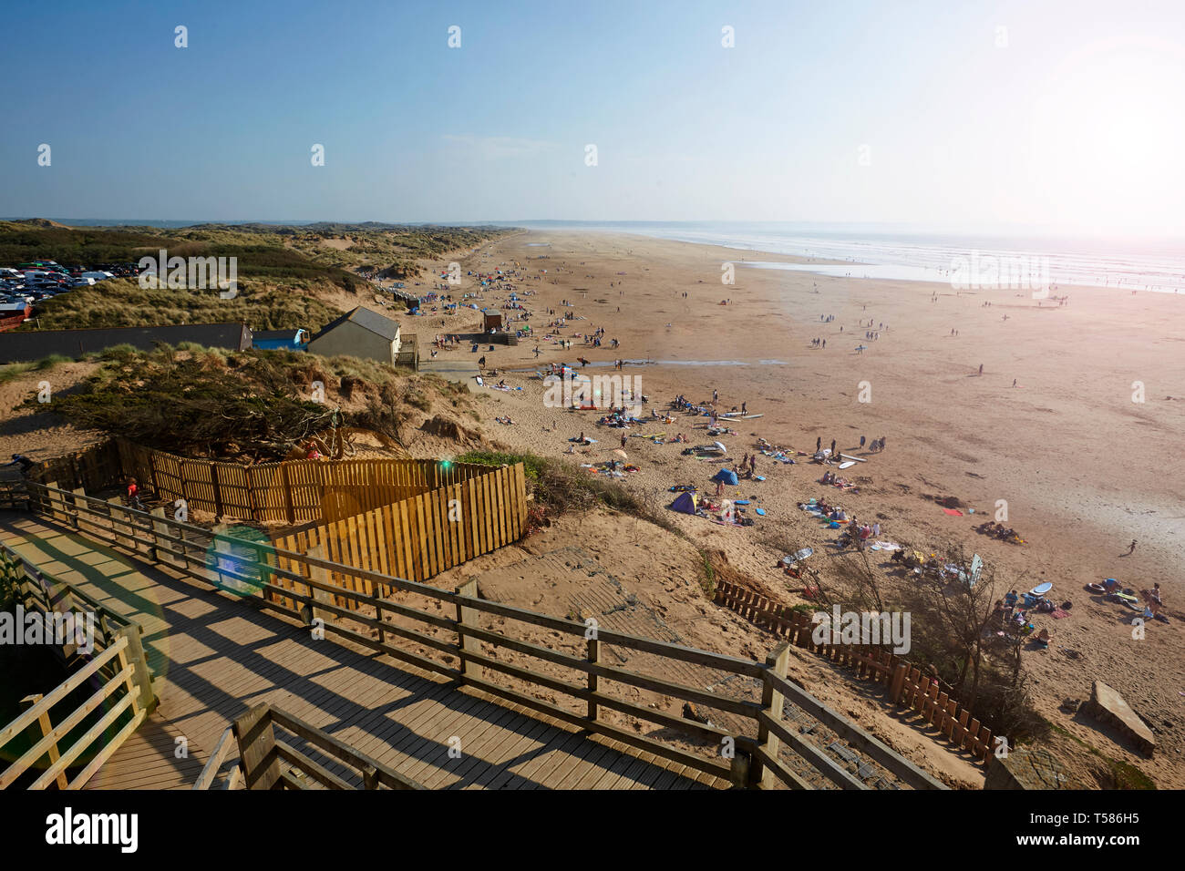 I turisti su Saunton sands beach in North Devon durante la Pasqua 2019 onda di calore con la scheda a piedi in primo piano Foto Stock