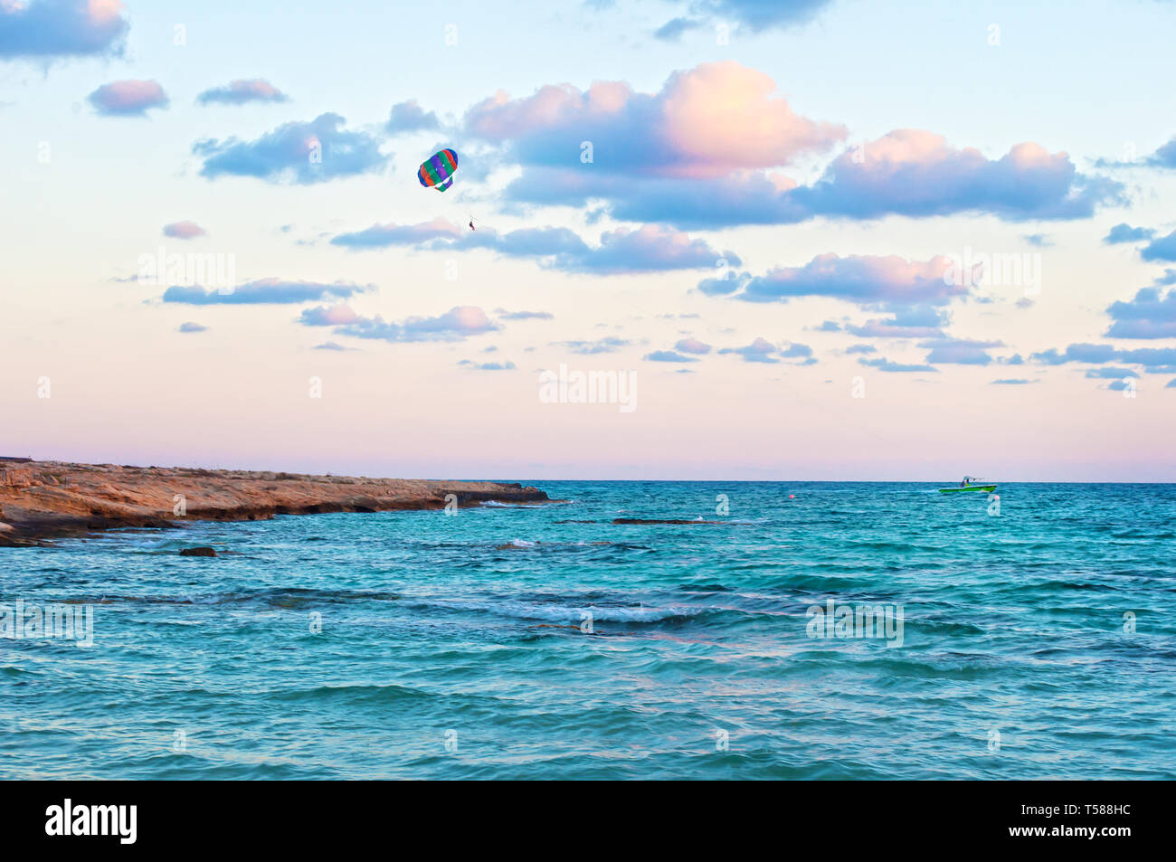 Immagine vibrante di persone parasailing su un paracadute colorato bulled da una barca sullo sfondo del mare blu acqua e cielo nuvoloso. Concetto di estrema Foto Stock
