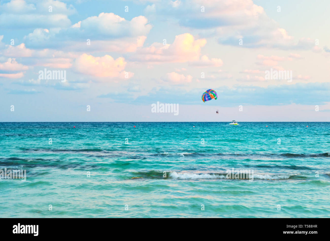Immagine vibrante di persone parasailing su un paracadute colorato bulled da una barca sullo sfondo del mare blu acqua e cielo nuvoloso. Concetto di estrema Foto Stock