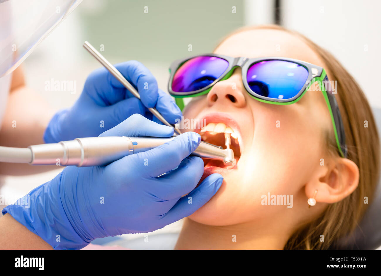 Igienista dentale di eseguire la lucidatura dei denti procedura per preteen girl in pazienti pediatrici clinica dentale. Medico utilizzando prophy pennello sul manipolo per rimuovere har Foto Stock