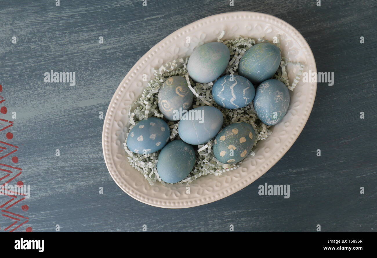 Dipinto di uova di Pasqua, colorato con un colorante dal cavolo rosso, su un gesso dipinto di blu distressed tavolo in legno Foto Stock