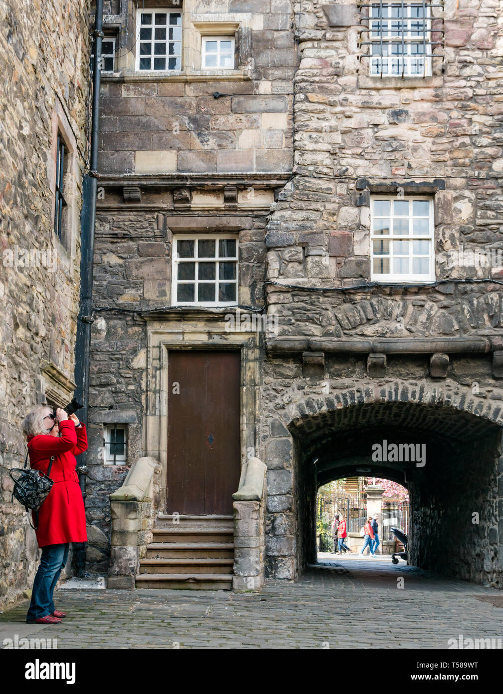 Senior donna che indossa cappotto rosso di scattare le foto del film Outlander ubicazione, Bakehouse vicino, Royal Mile di Edimburgo, Scozia, Regno Unito Foto Stock