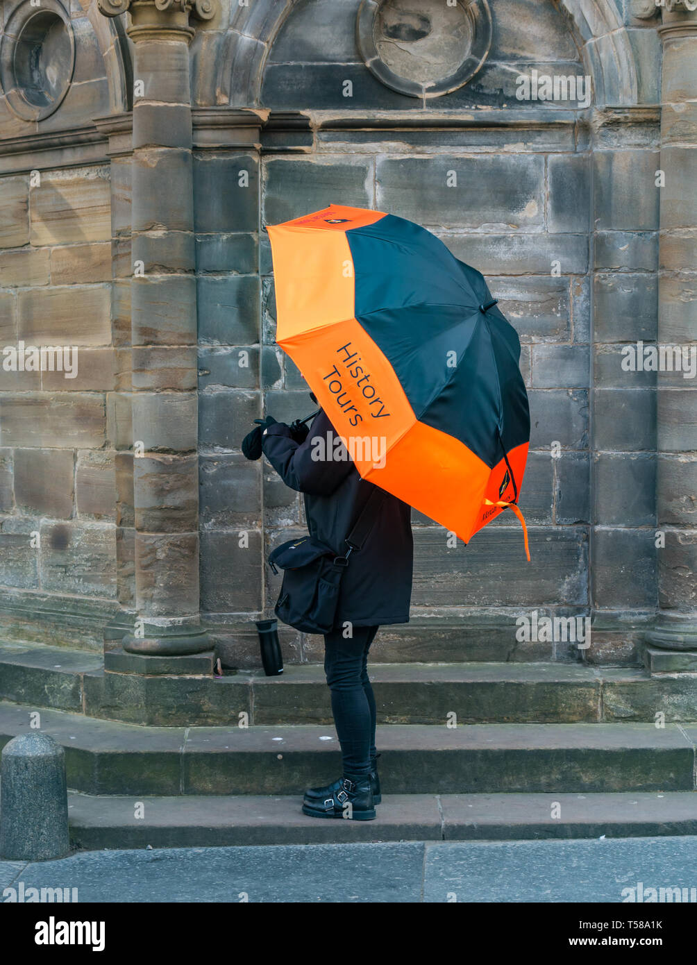 Donna che mantiene grandi vivacemente colorato ombrello pubblicità turistiche guidate tour storico, Mercat Cross, Royal Mile di Edimburgo, Scozia, Regno Unito Foto Stock