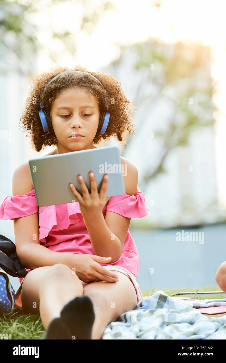Ragazza concentrato in cuffie utilizzando tablet Foto Stock