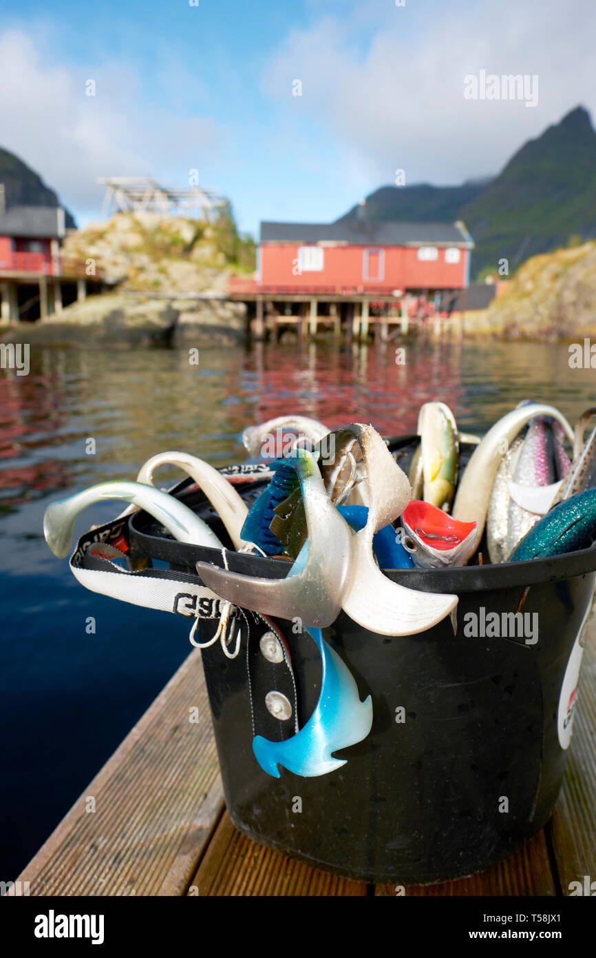 Una benna di turistici mare esche artificiali e Rorbu tradizionale norvegese case di pescatori nel villaggio di pescatori di Å nelle isole Lofoten in Norvegia Foto Stock