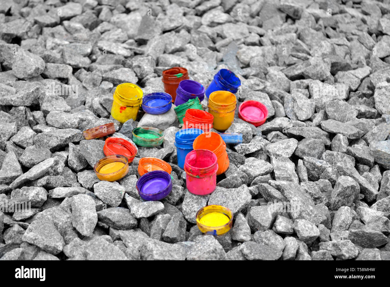 Colorato piccoli barattoli di vernice può giacere su un ciottolo grigio close-up Foto Stock