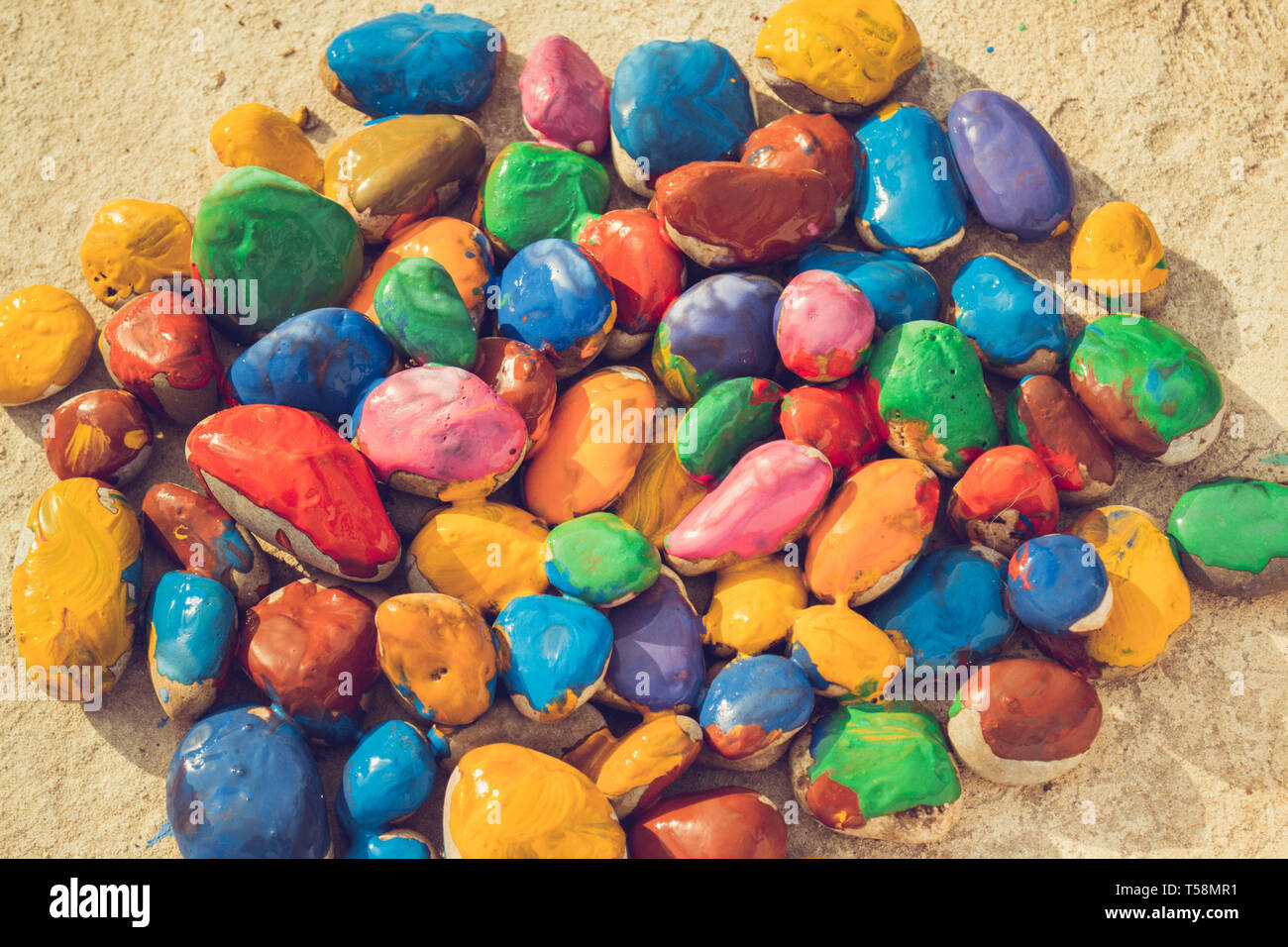 Pietre colorate di vernici colorate in diversi colori giacciono su una superficie piana. Close-up Foto Stock