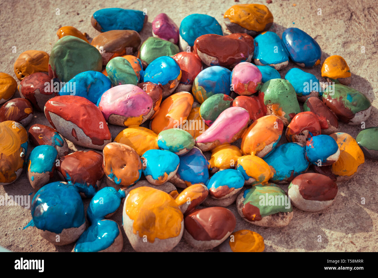 Pietre colorate di vernici colorate in diversi colori giacciono su una superficie piana. Close-up Foto Stock