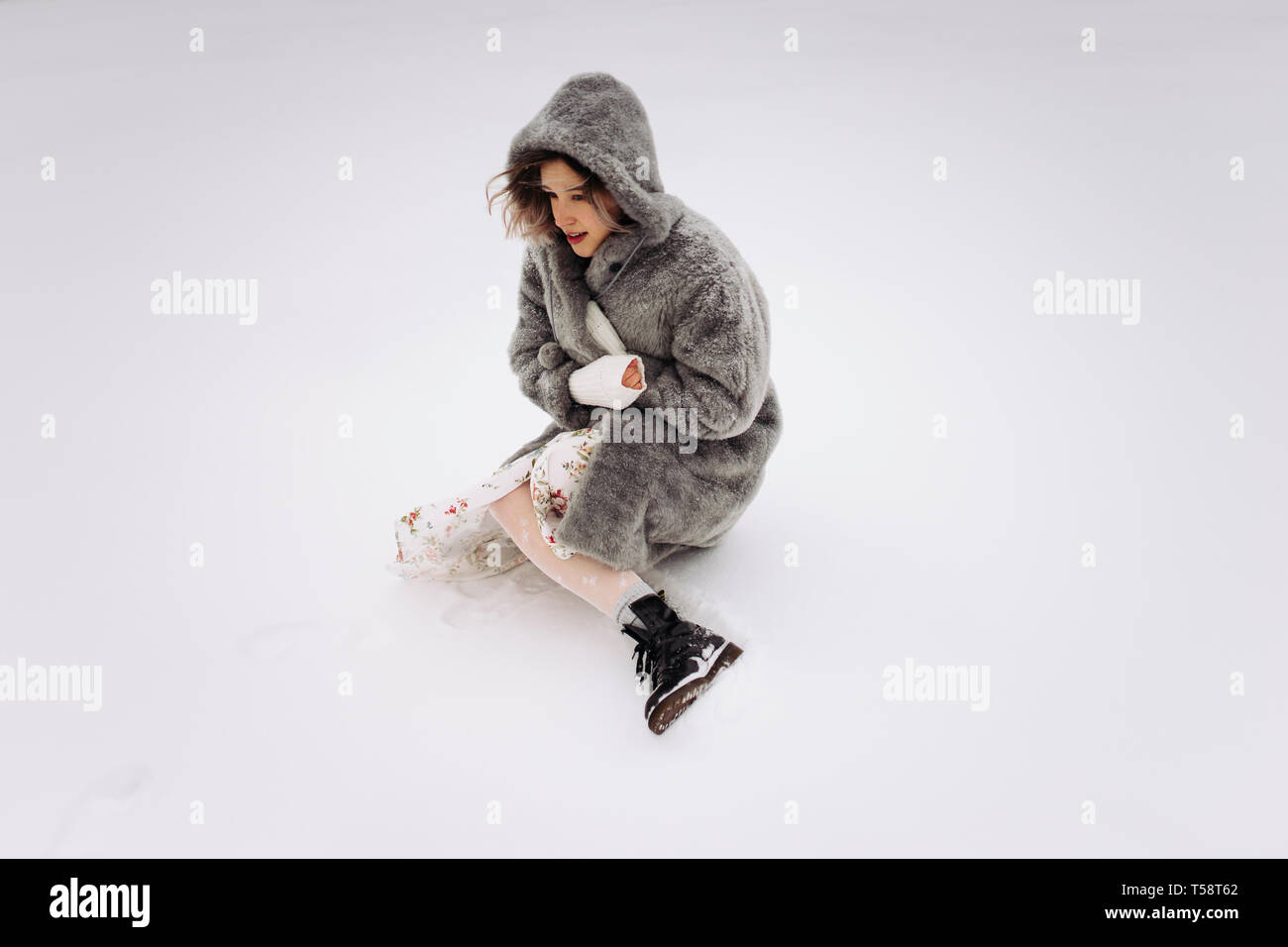 Una donna in pelliccia si siede su un lago innevato in inverno Foto Stock