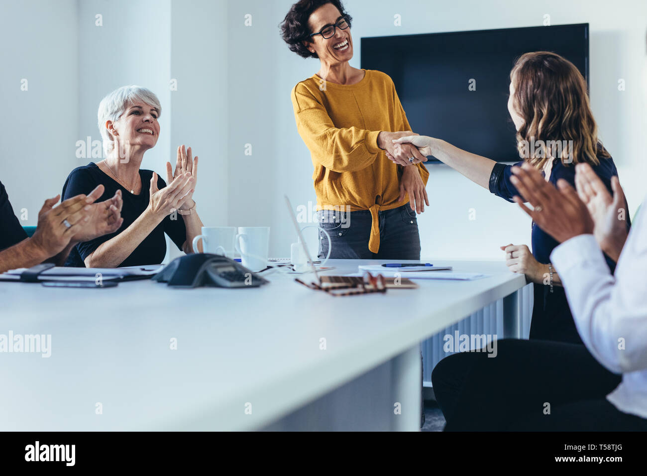 donne d'affari che stringono la mano e durante una riunione d'affari. Donne professioniste che stringono la mano con il team seduto battendo le mani dopo un m di successo Foto Stock