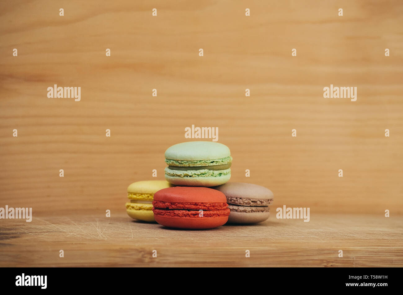 Quattro gustosi colorati macarons francese isolato su texture di legno Foto Stock