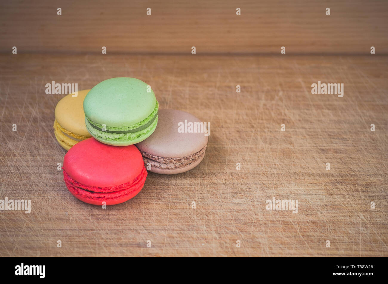 Quattro gustosi colorati macarons francese isolato su texture di legno Foto Stock