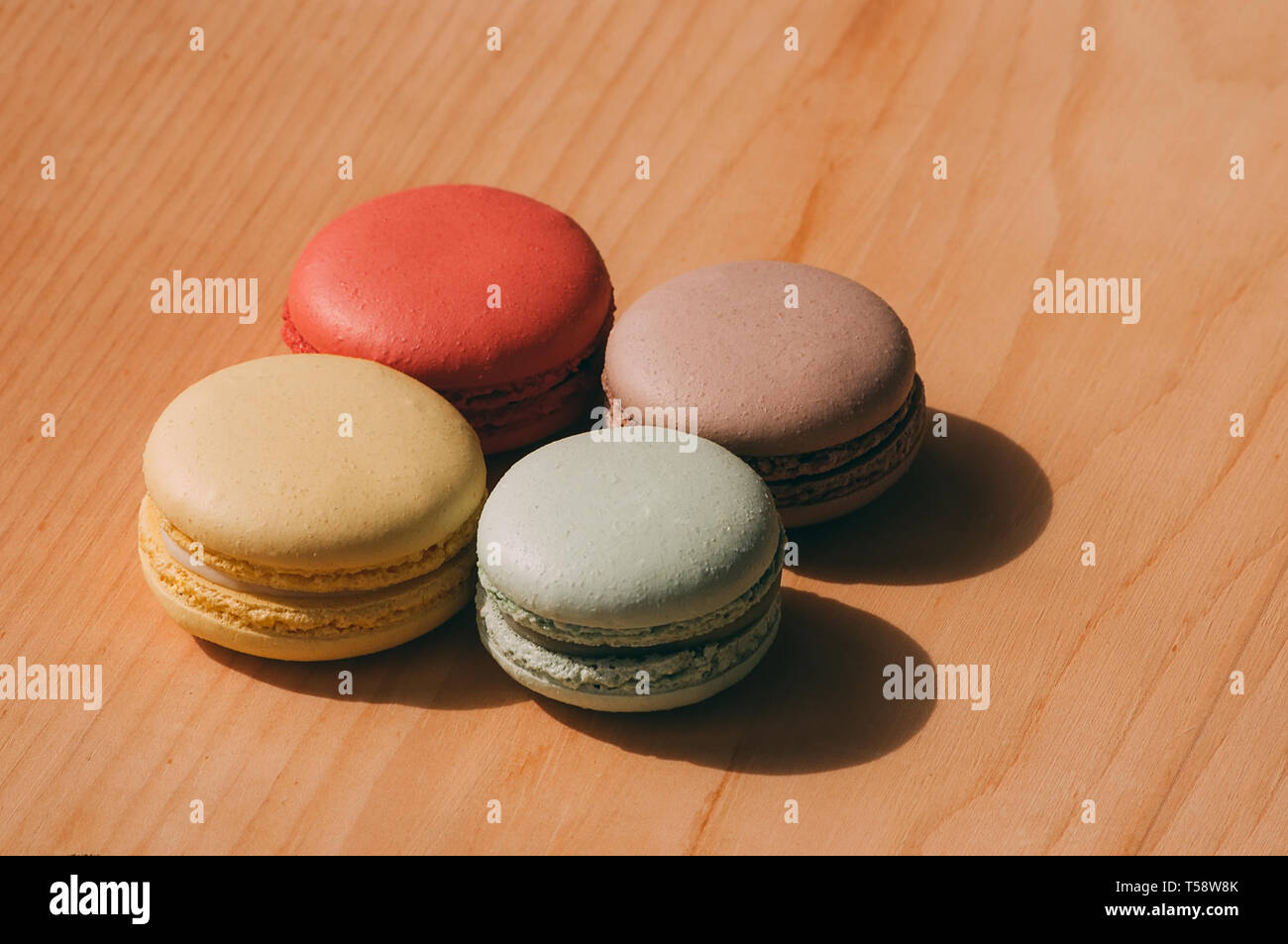 Quattro gustosi colorati macarons francese isolato su texture di legno Foto Stock