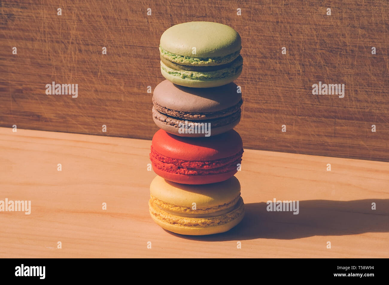 Quattro gustosi colorati macarons francese isolato su texture di legno Foto Stock