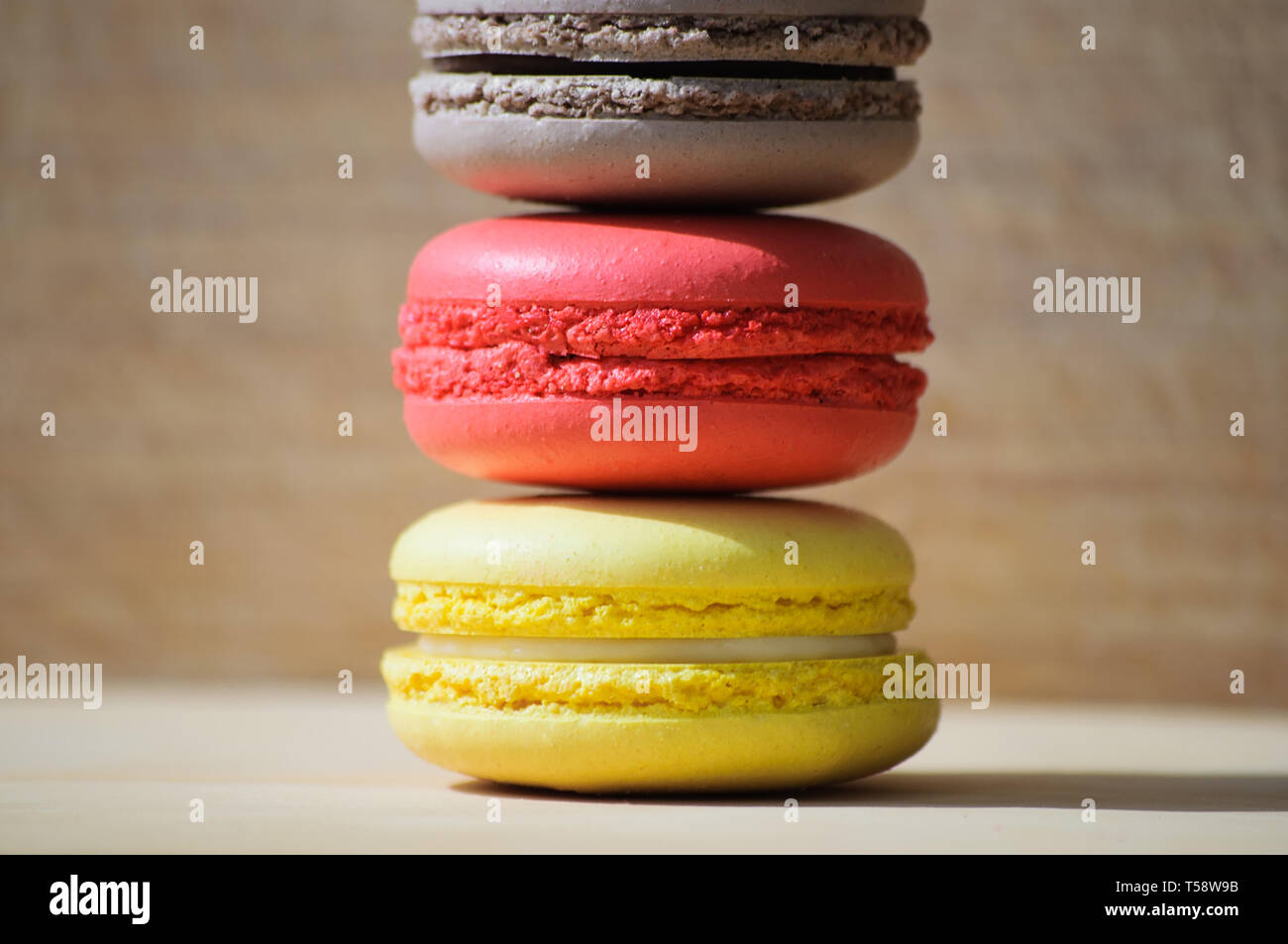 Quattro gustosi colorati macarons francese isolato su texture di legno Foto Stock