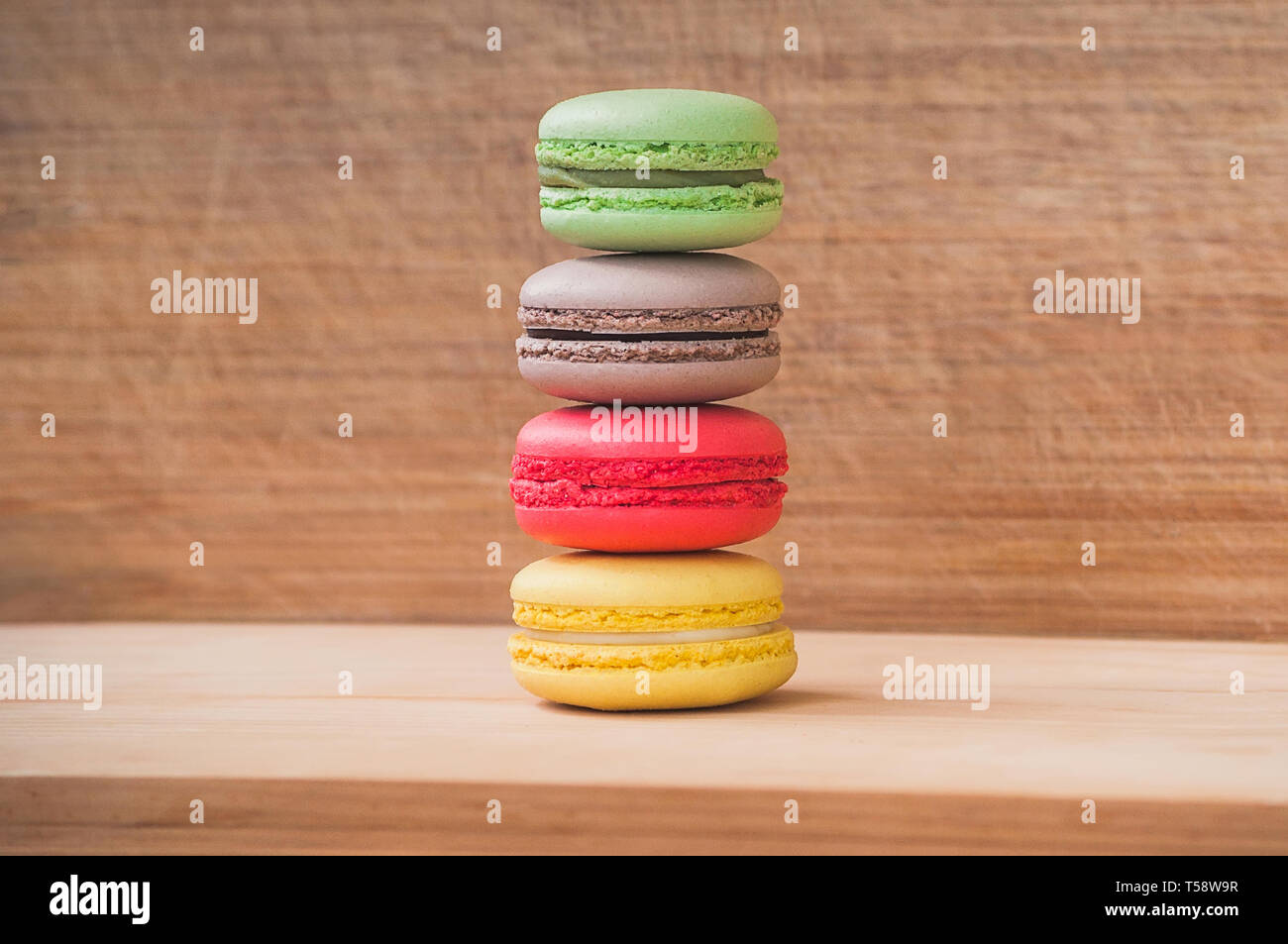 Quattro gustosi colorati macarons francese isolato su texture di legno Foto Stock