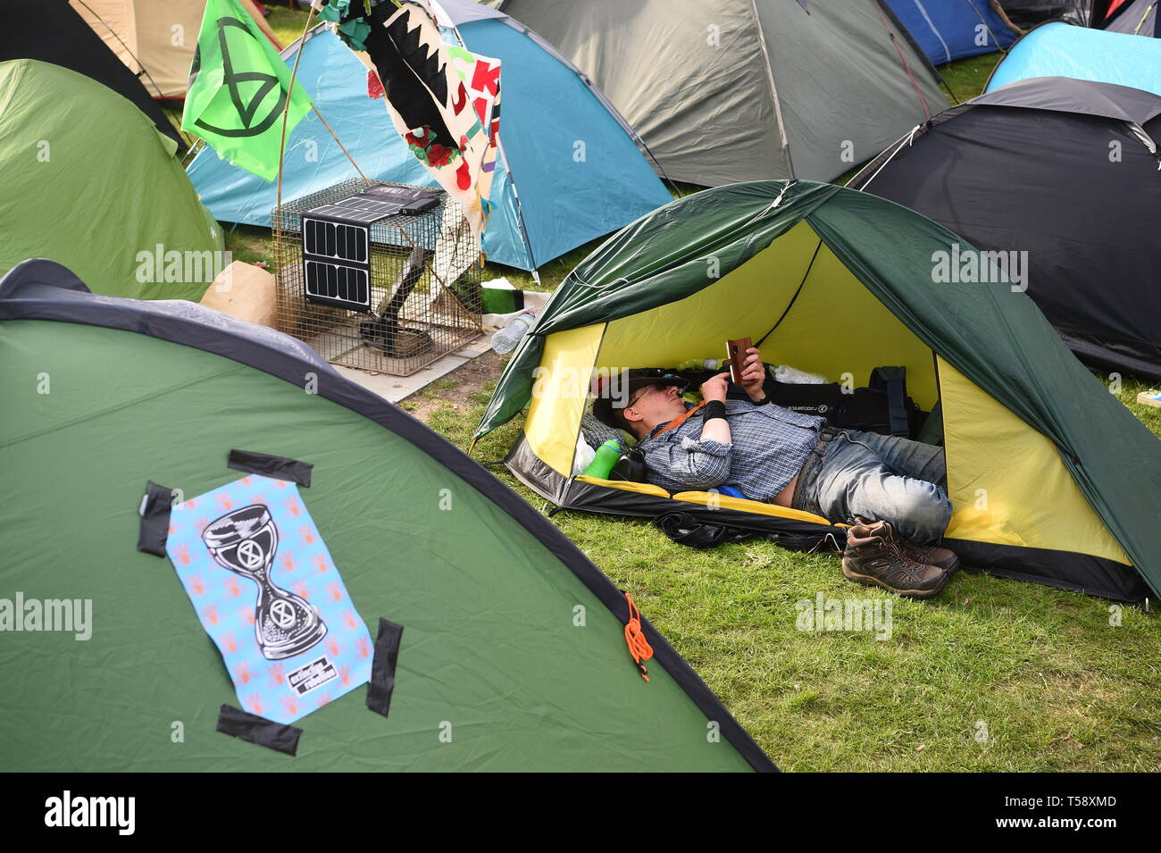 Un uomo riposa nella sua tenda nella ribellione di estinzione (XR) camp in Marble Arch, Londra. Più di mille persone sono state arrestate durante una settimana di cambiamenti climatici proteste a Londra come la polizia ha autorizzato i blocchi stradali responsabili per interruzioni nella capitale. Foto Stock