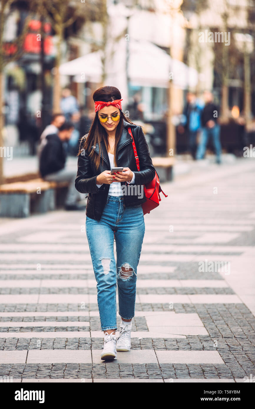 Ritratto di giovane bella ragazza alla moda in Eleganti occhiali da sole utilizzando smart phone. Foto Stock