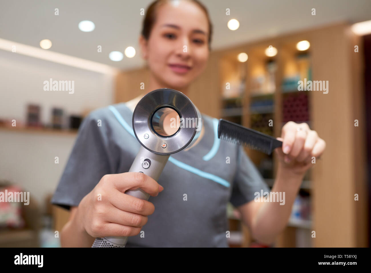 Utilizzando i moderni asciugacapelli e il pettine per acconciature Foto Stock