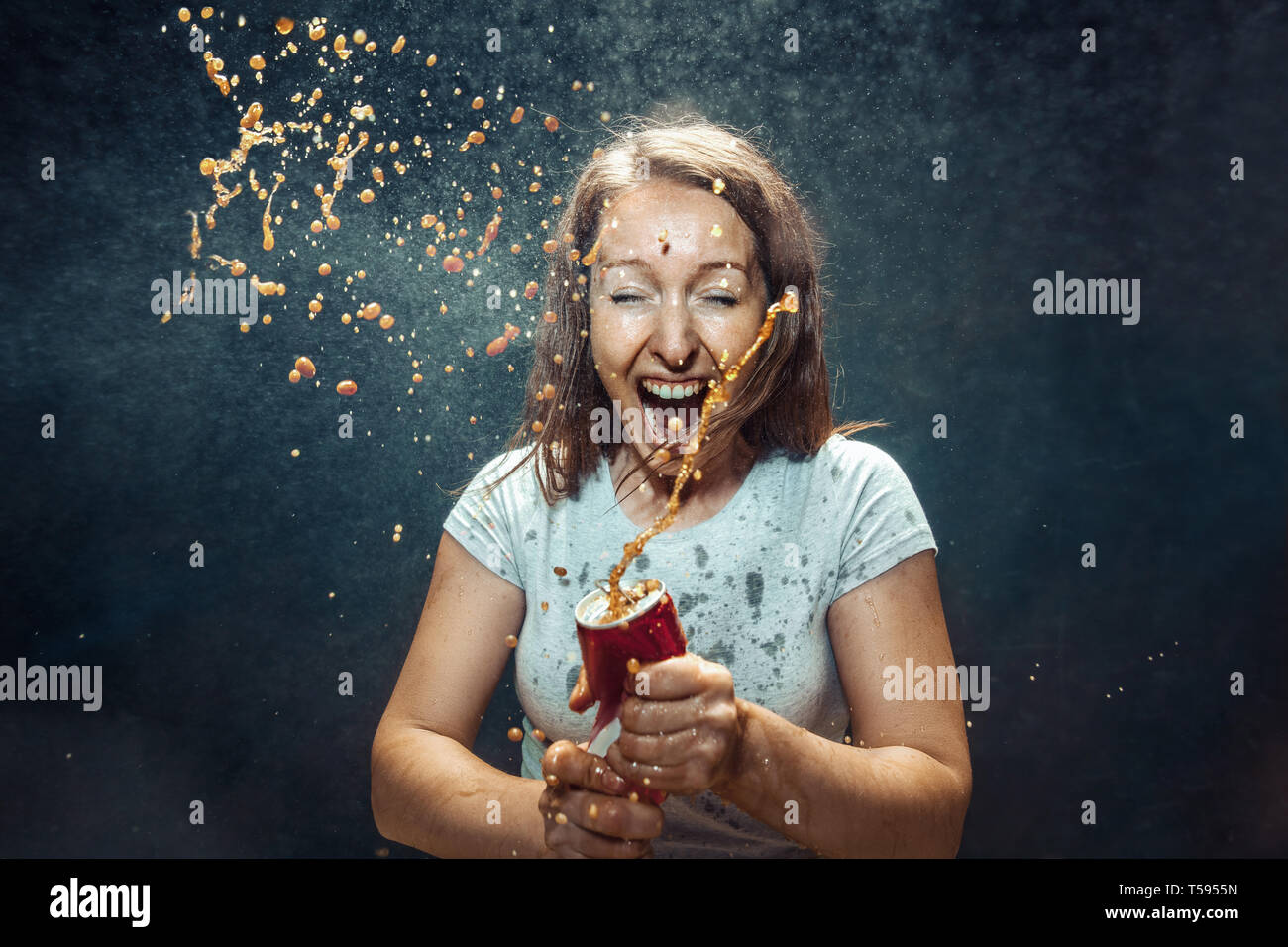 Donna di bere una coca cola in studio. Giovani felici sorridente ragazza caucasica apertura può con cola e godendo di spruzzo. L'immagine pubblicitaria circa drink preferito. Lo stile di vita e le emozioni umane concetto. Foto Stock